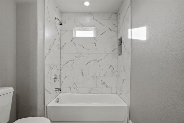 bathroom featuring toilet and tiled shower / bath