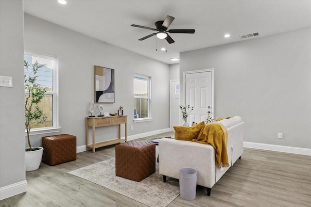 living area with a wealth of natural light, ceiling fan, and light hardwood / wood-style floors