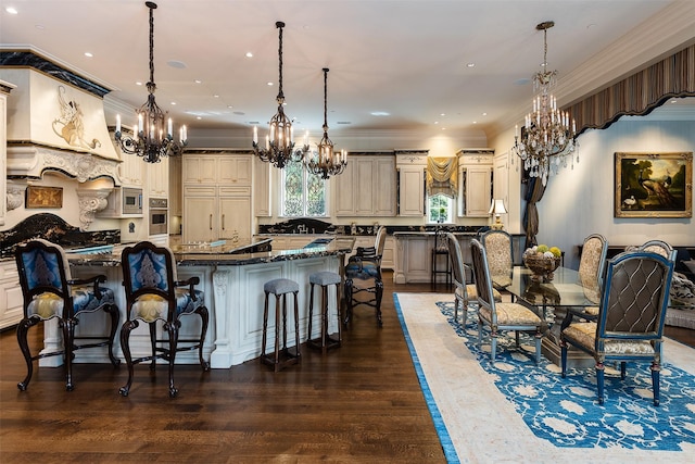 kitchen with a kitchen bar, cream cabinets, dark stone counters, and pendant lighting