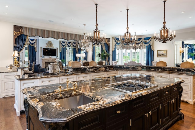 kitchen with a large island, sink, cooktop, dark hardwood / wood-style floors, and dark stone counters