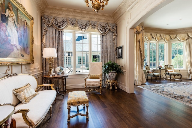 living area with a chandelier, a healthy amount of sunlight, dark hardwood / wood-style floors, and ornamental molding