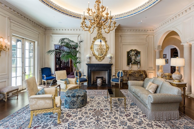 living area with a chandelier, dark hardwood / wood-style flooring, ornate columns, and ornamental molding