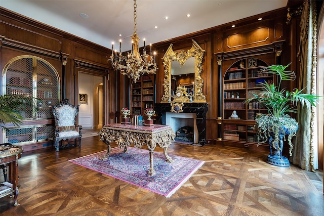 office featuring wood walls, parquet floors, a fireplace, and a chandelier