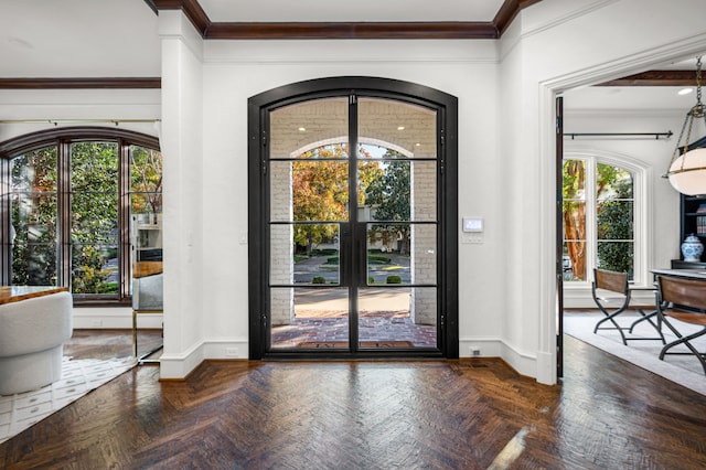 entrance foyer with dark parquet flooring, a wealth of natural light, and ornamental molding