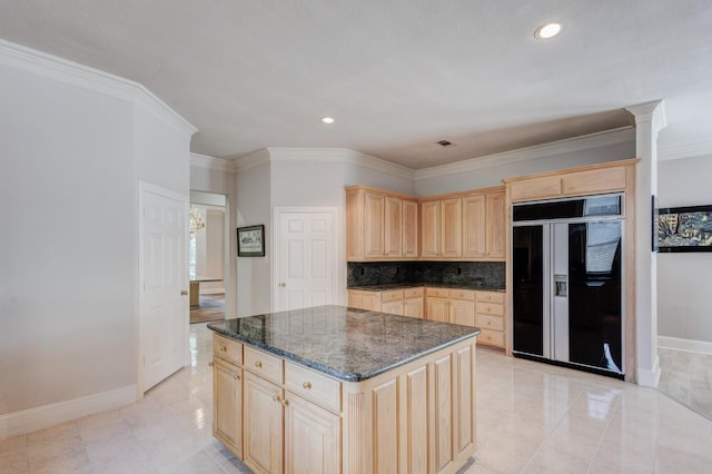 kitchen featuring light brown cabinetry, a center island, dark stone counters, and built in fridge