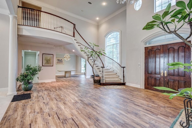 entrance foyer featuring a towering ceiling, a wealth of natural light, and ornamental molding