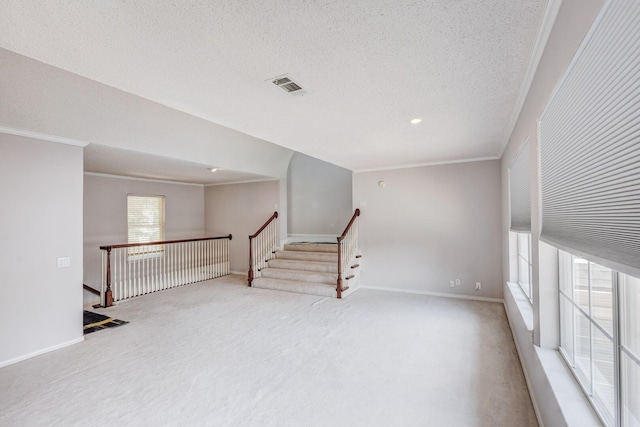 unfurnished room featuring light carpet, crown molding, and a textured ceiling