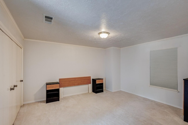 unfurnished room with a textured ceiling, light colored carpet, and crown molding