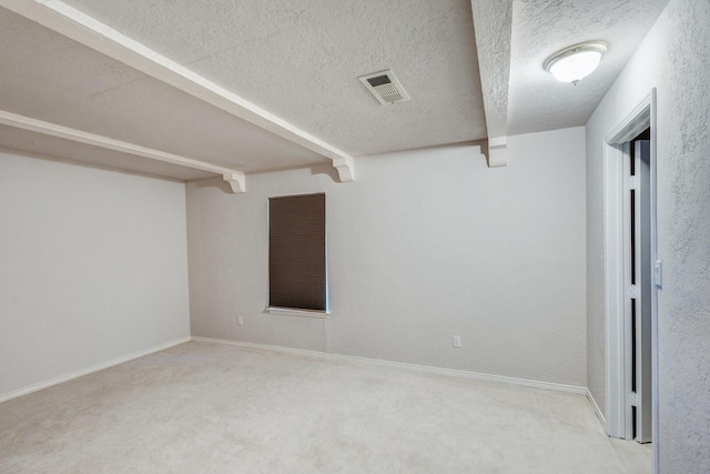 empty room featuring light carpet, a textured ceiling, and beamed ceiling