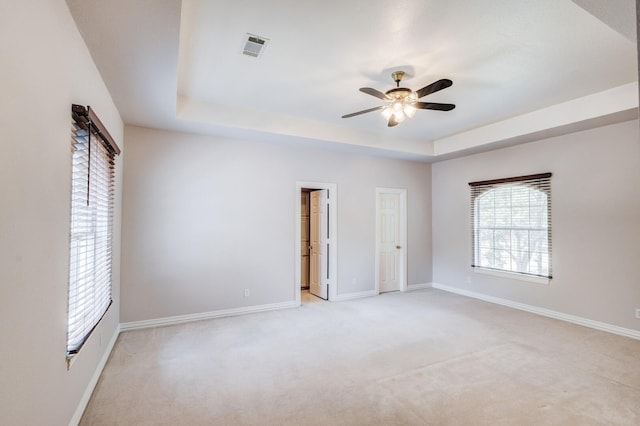 carpeted spare room featuring a raised ceiling and ceiling fan