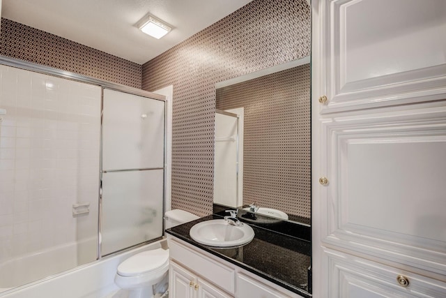 full bathroom featuring vanity, toilet, and bath / shower combo with glass door