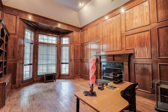 office space featuring wooden walls, vaulted ceiling, and hardwood / wood-style flooring