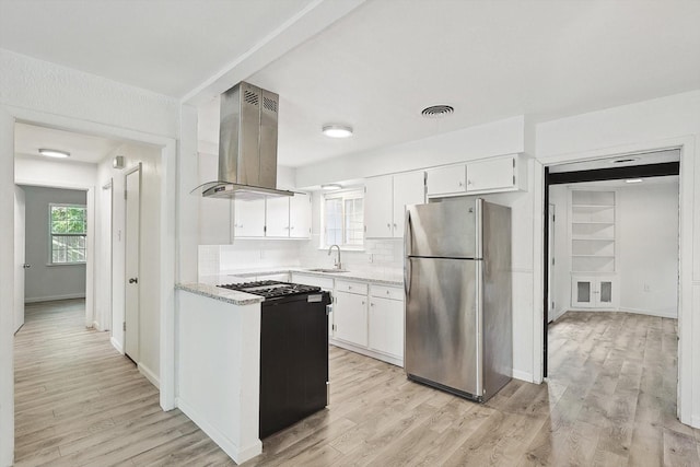 kitchen featuring decorative backsplash, exhaust hood, white cabinets, light hardwood / wood-style floors, and stainless steel refrigerator