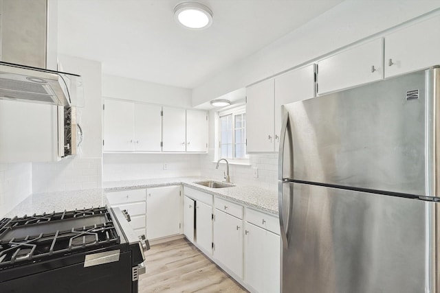 kitchen featuring stainless steel fridge, white cabinetry, sink, and gas stove