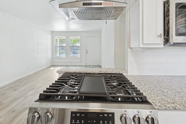 details featuring light stone counters, backsplash, stove, extractor fan, and white cabinets