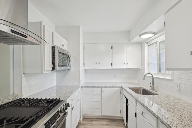 kitchen featuring sink, white cabinets, wall chimney range hood, and appliances with stainless steel finishes