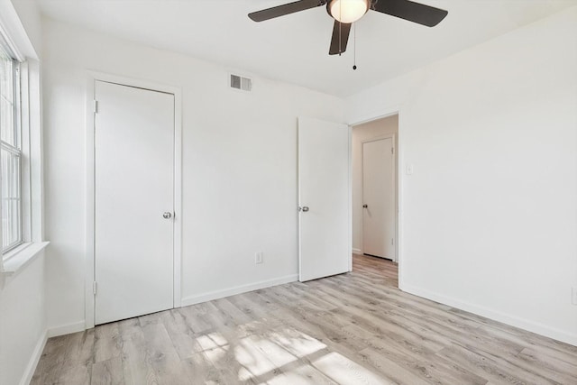 unfurnished bedroom featuring multiple windows, ceiling fan, a closet, and light wood-type flooring