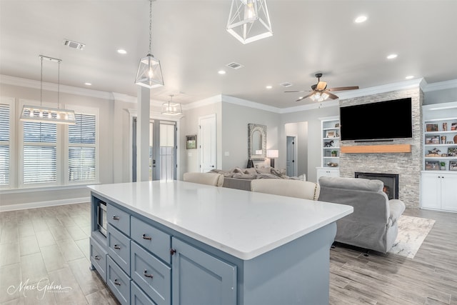 kitchen with built in shelves, a fireplace, a kitchen island, and pendant lighting