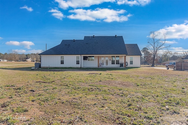 rear view of house with central AC and a lawn