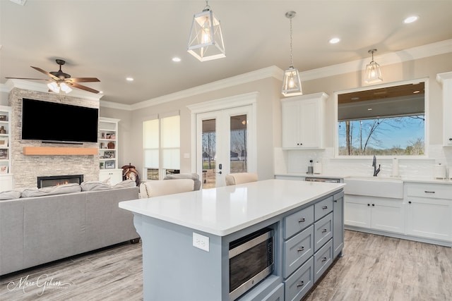 kitchen with a fireplace, ceiling fan, decorative light fixtures, white cabinets, and a center island