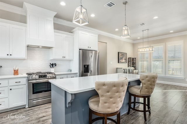 kitchen with white cabinetry, a kitchen island, stainless steel appliances, and decorative light fixtures