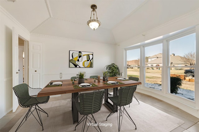 tiled dining room featuring ornamental molding and vaulted ceiling