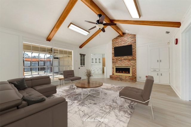 living room featuring ceiling fan, light wood-type flooring, vaulted ceiling with beams, and a fireplace