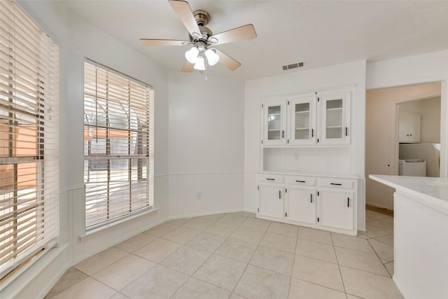 unfurnished dining area with ceiling fan and light tile patterned floors