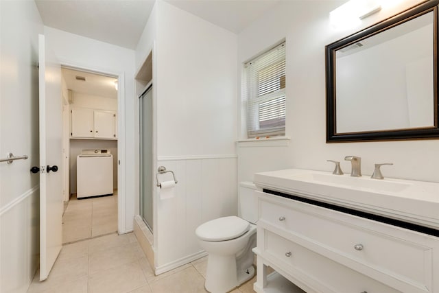 bathroom featuring tile patterned flooring, toilet, vanity, washer / dryer, and an enclosed shower