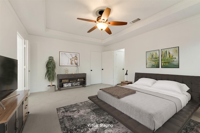 carpeted bedroom with a raised ceiling, ceiling fan, and ornamental molding