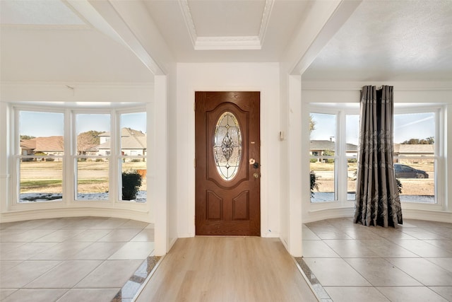 entryway featuring light tile patterned floors, a tray ceiling, and crown molding