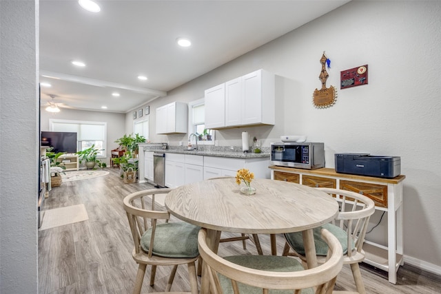 dining area with sink, ceiling fan, and light wood-type flooring