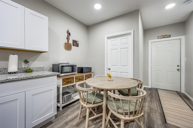 kitchen featuring white cabinets, light hardwood / wood-style floors, and light stone countertops