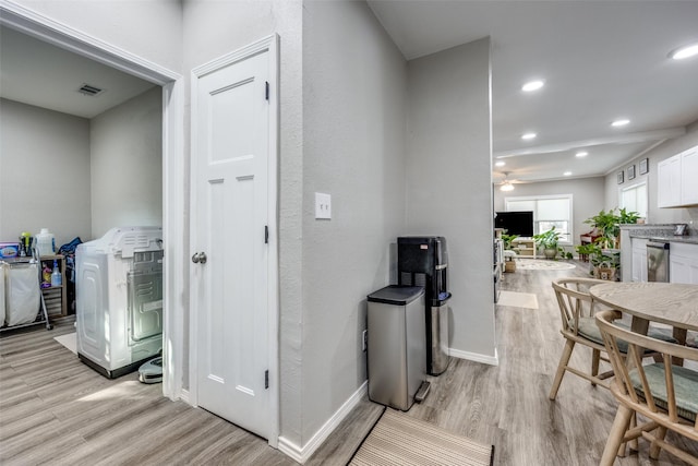 interior space with washer / clothes dryer, ceiling fan, light hardwood / wood-style flooring, and white cabinetry