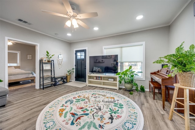 living room featuring ceiling fan, light hardwood / wood-style floors, and crown molding