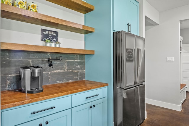 kitchen with butcher block countertops, blue cabinets, and stainless steel refrigerator