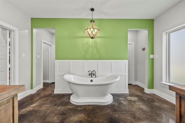 bathroom with a washtub, concrete floors, and a notable chandelier