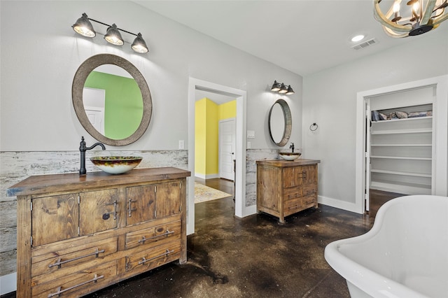 bathroom with a chandelier, a washtub, vanity, and concrete floors