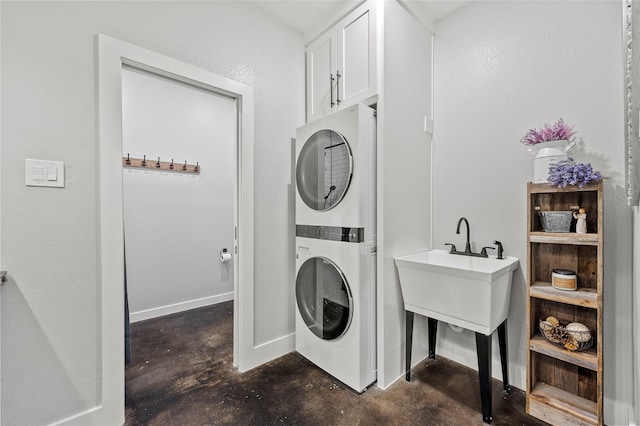 clothes washing area with cabinets and stacked washing maching and dryer