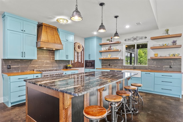 kitchen with custom range hood, blue cabinets, built in microwave, and a kitchen island