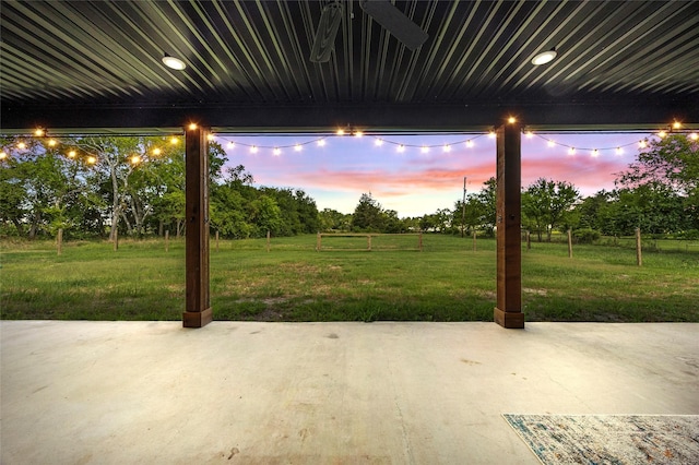 patio terrace at dusk featuring a yard and ceiling fan