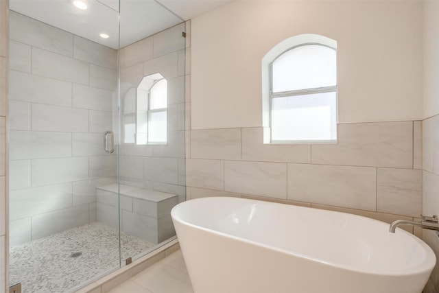 bathroom featuring a wealth of natural light, tile patterned flooring, plus walk in shower, and tile walls