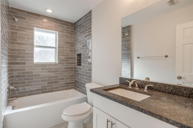 full bathroom featuring tiled shower / bath, vanity, and toilet