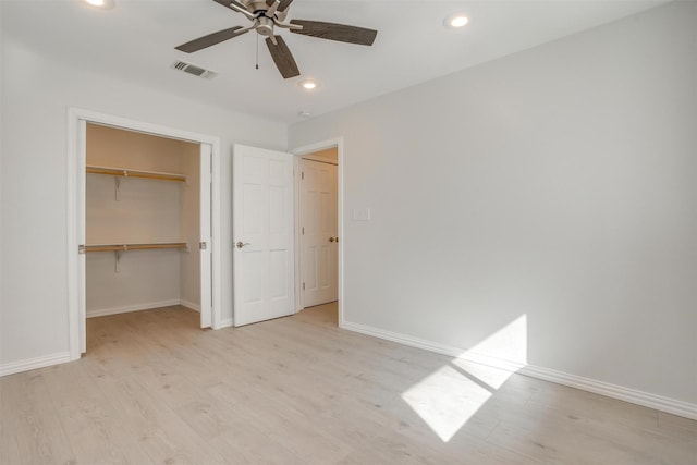 unfurnished bedroom with a closet, light hardwood / wood-style floors, a spacious closet, and ceiling fan