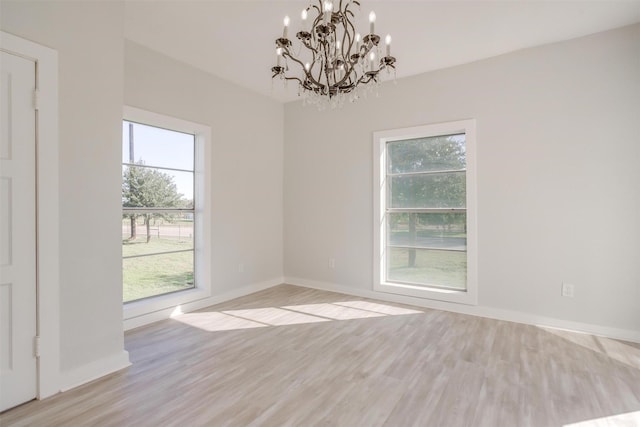 empty room with light hardwood / wood-style flooring and an inviting chandelier