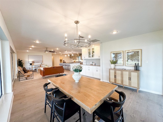 dining area featuring ceiling fan with notable chandelier and light wood-type flooring