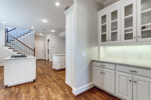 kitchen featuring kitchen peninsula, white cabinetry, and crown molding