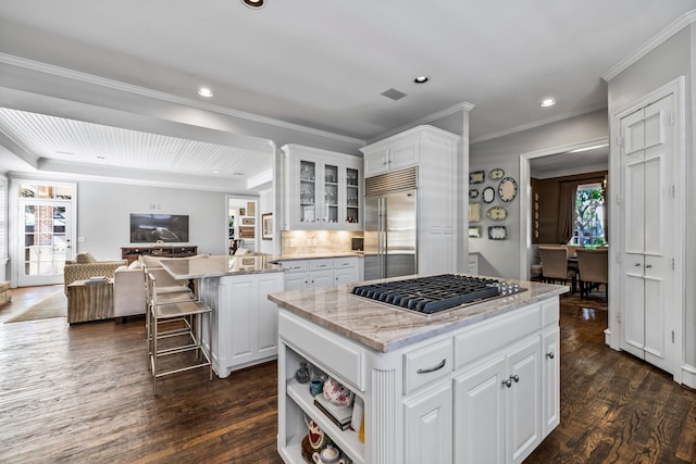 kitchen with white cabinets, appliances with stainless steel finishes, a kitchen island, and light stone counters