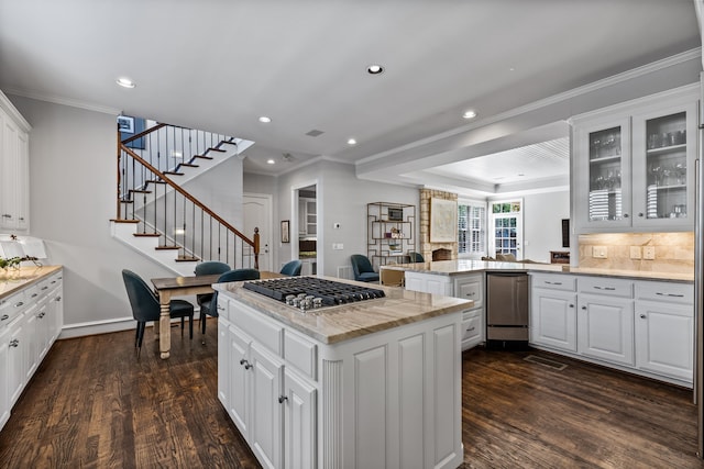 kitchen featuring kitchen peninsula, light stone countertops, white cabinetry, and stainless steel gas cooktop