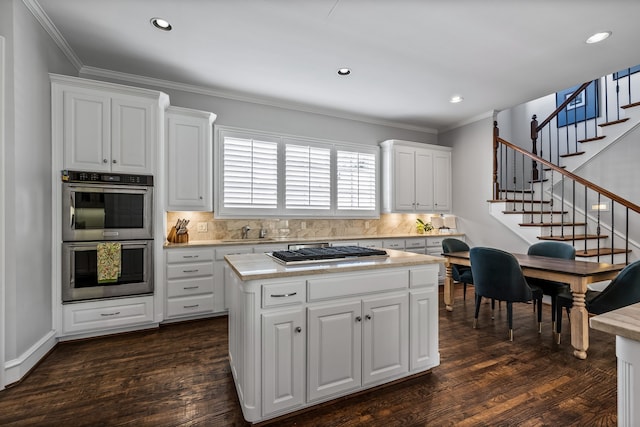 kitchen featuring dark wood-type flooring, white cabinets, tasteful backsplash, a kitchen island, and stainless steel appliances